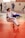 A martial arts dojo features several practitioners in white and blue gi uniforms engaged in training on red and gray mats. The central figure is performing a martial arts technique, surrounded by others practicing and discussing techniques.