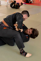 Male BJJ competitor executing a precise armbar submission in a crowded competition setting.