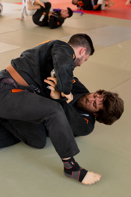 Instructor demonstrating a jiu-jitsu technique with focused students watching closely