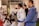 A group of individuals dressed in martial arts gis, gathered in a dojo. Most are seated, attentively listening, while one person in a blue gi stands prominently. The setting appears focused and disciplined, with some written notes visible on a bulletin board in the background.