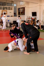 Adults sparring intensely during a Brazilian Jiu-Jitsu class.