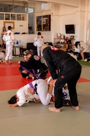 A beginner jiu-jitsu class practicing basic moves on mats with instructor guidance.