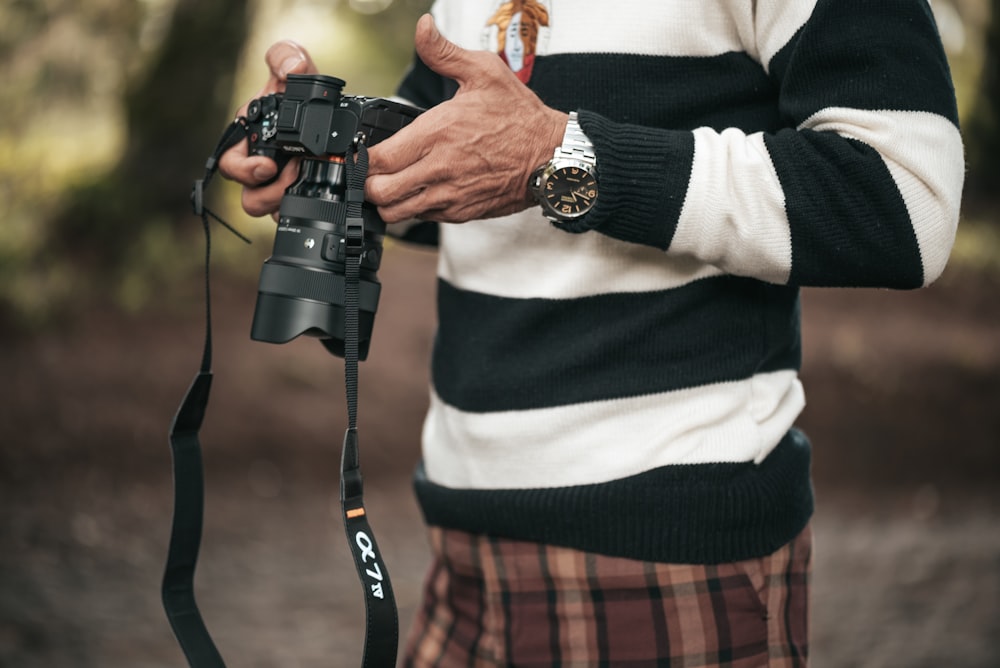 Un hombre sosteniendo una cámara en sus manos