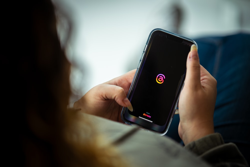 a woman holding a cell phone with a logo on it