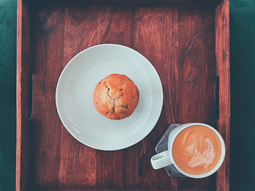 a muffin on a plate next to a cup of coffee