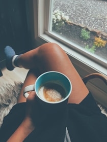 A busy professional relaxing on a cozy domestic getaway porch, sipping coffee with a smile.