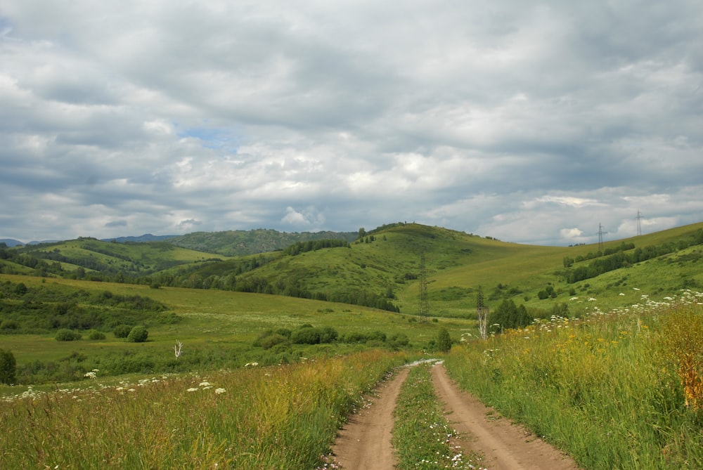 a dirt road going through a lush green valley