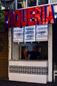 A chef preparing fresh tacos al pastor in an open kitchen with colorful decorations.