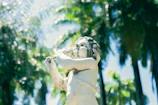 A serene statue of Lord Krishna playing the flute amidst a garden at dawn.