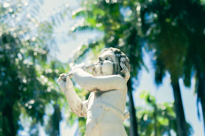 A serene statue of Lord Krishna playing the flute amidst a garden at dawn.