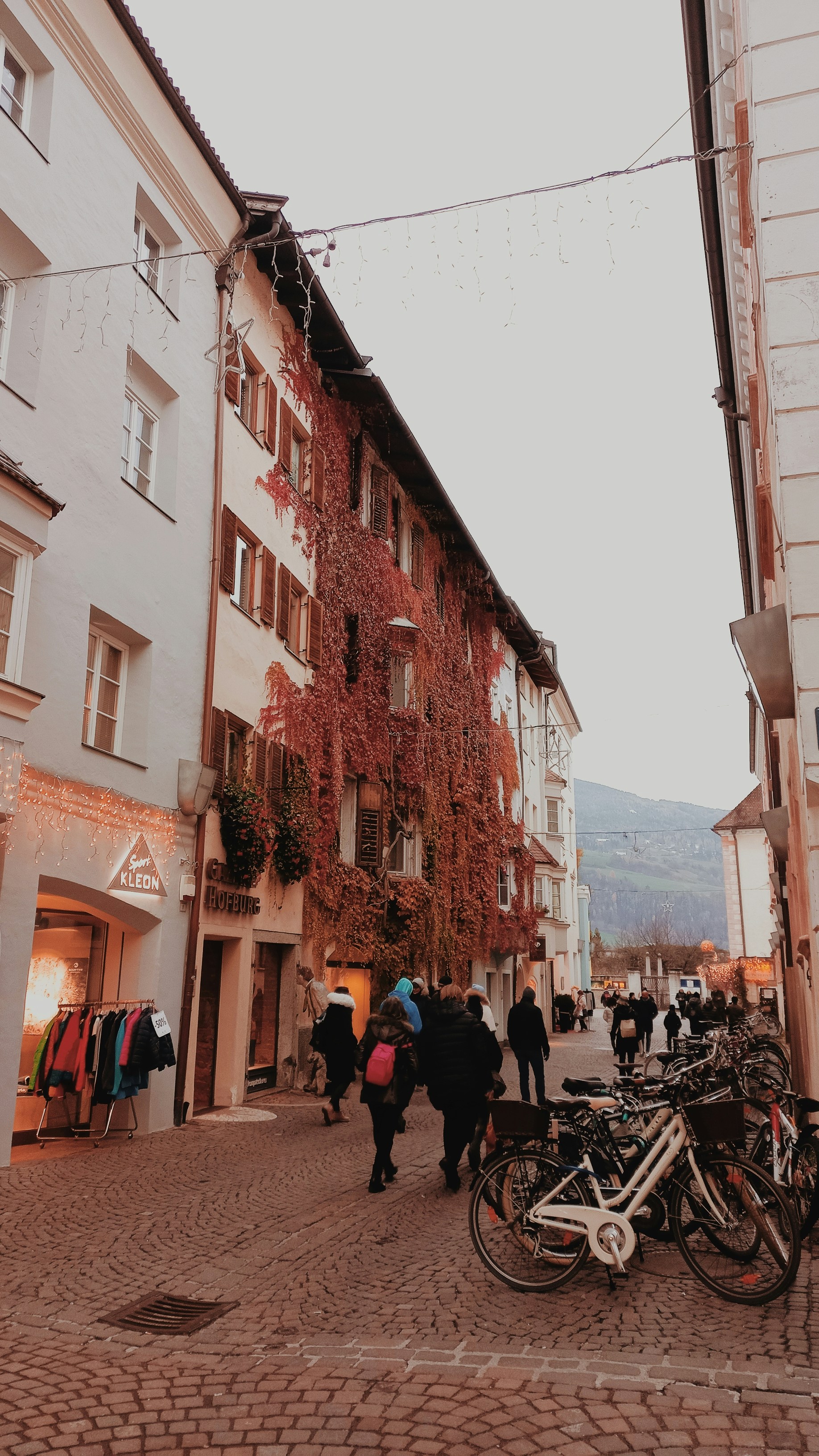 a group of people walking down a street next to tall buildings