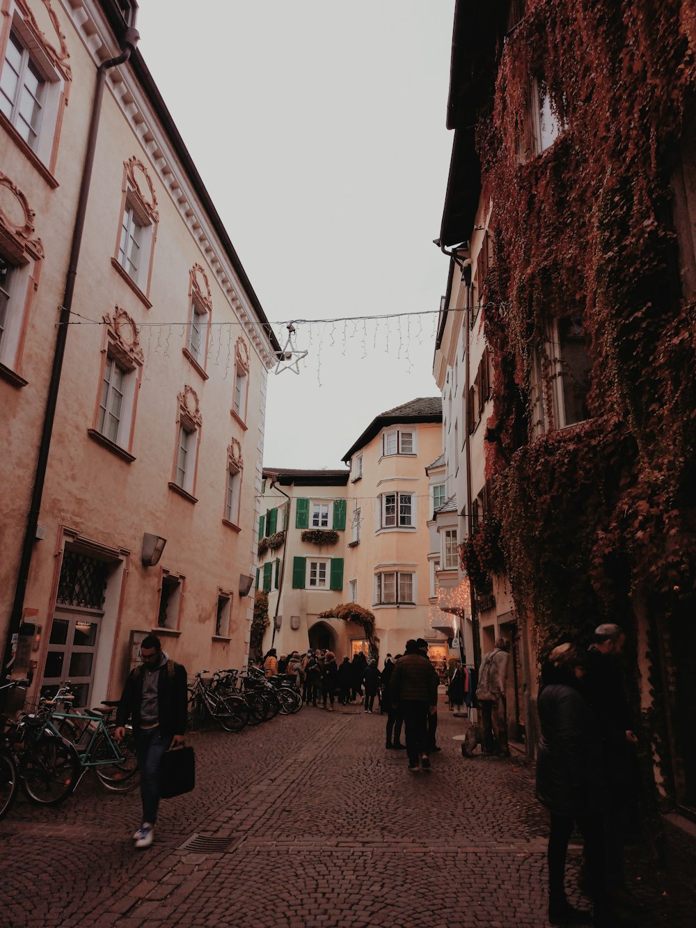 a group of people walking down a street next to tall buildings