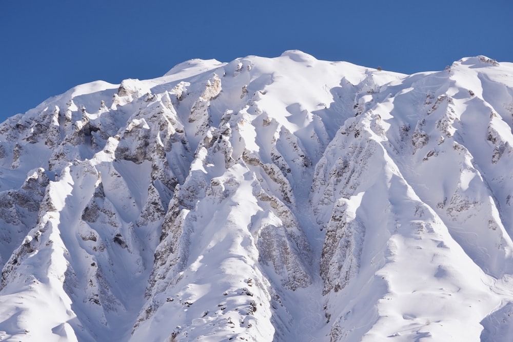 a large mountain covered in snow under a blue sky