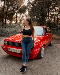 a woman standing next to a red car