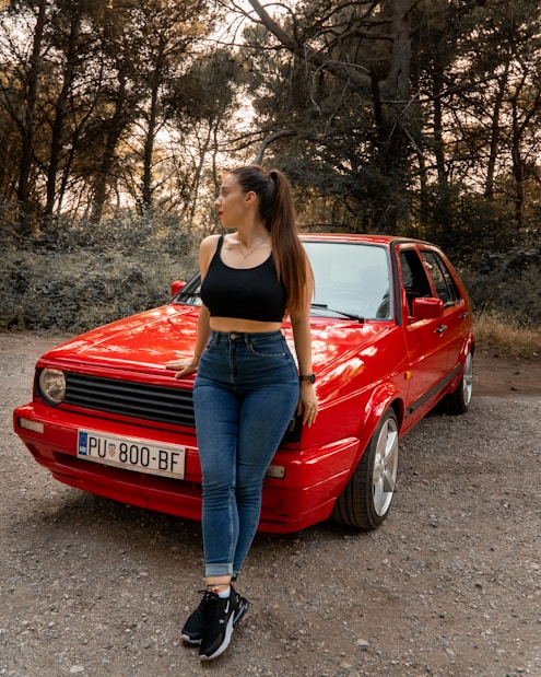 a woman standing next to a red car