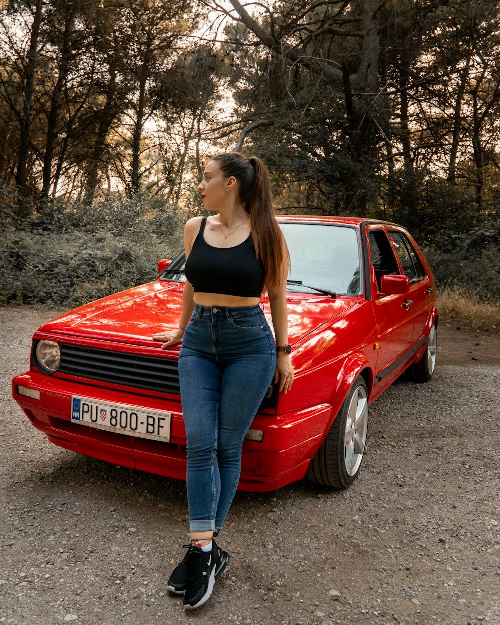 a woman standing next to a red car