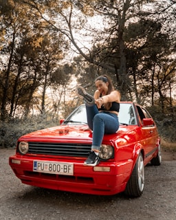 a woman sitting on the hood of a red car