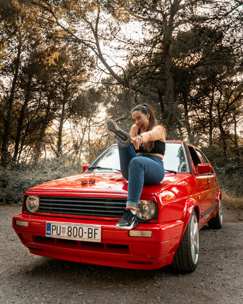 a woman sitting on the hood of a red car