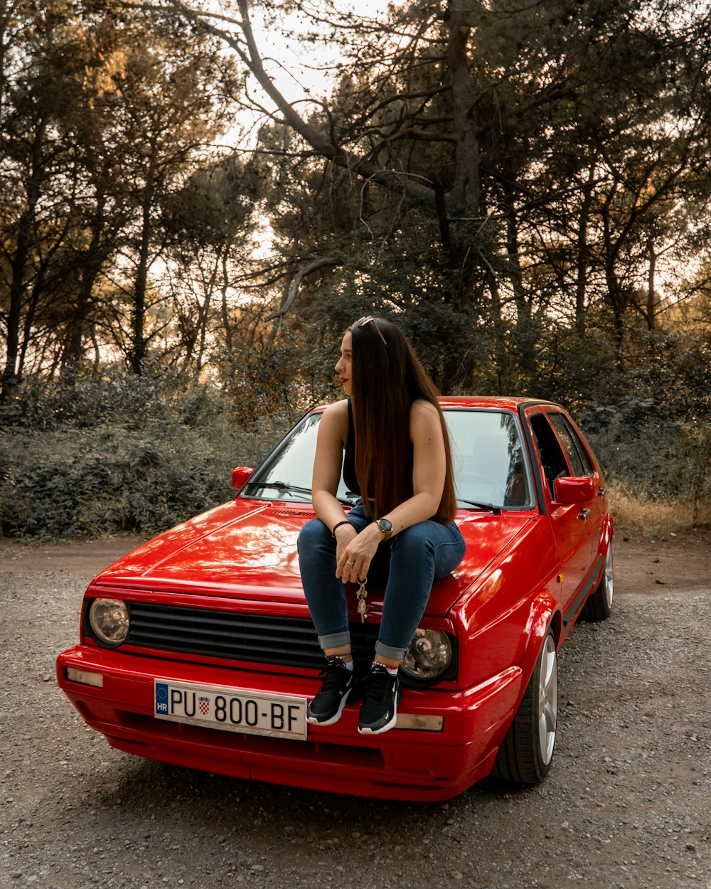 a woman sitting on the hood of a red car