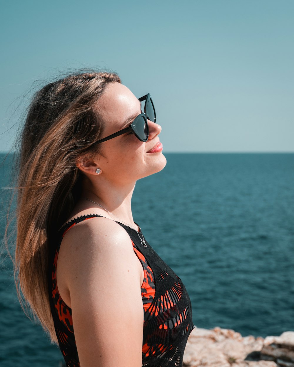 a woman wearing sunglasses looking out over the water