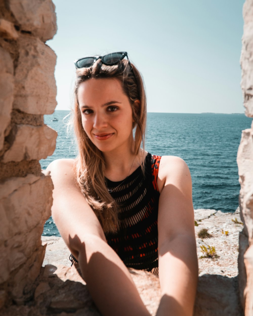 a woman sitting on a rock near the ocean