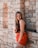 a woman leaning against a stone wall posing for a picture