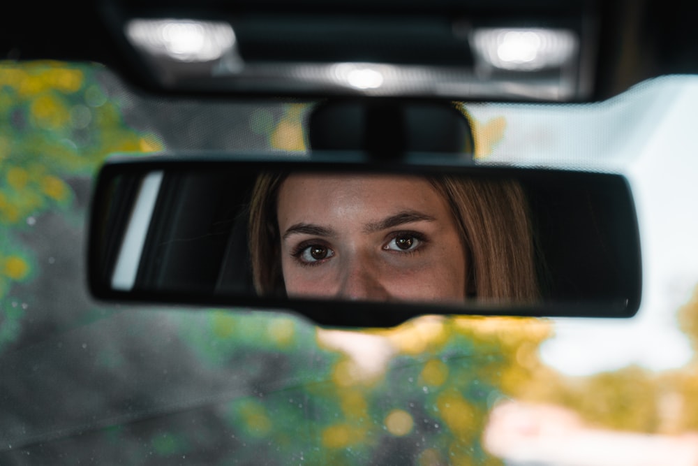 a woman's reflection in a rear view mirror