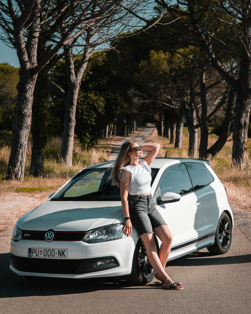 a woman standing next to a white car