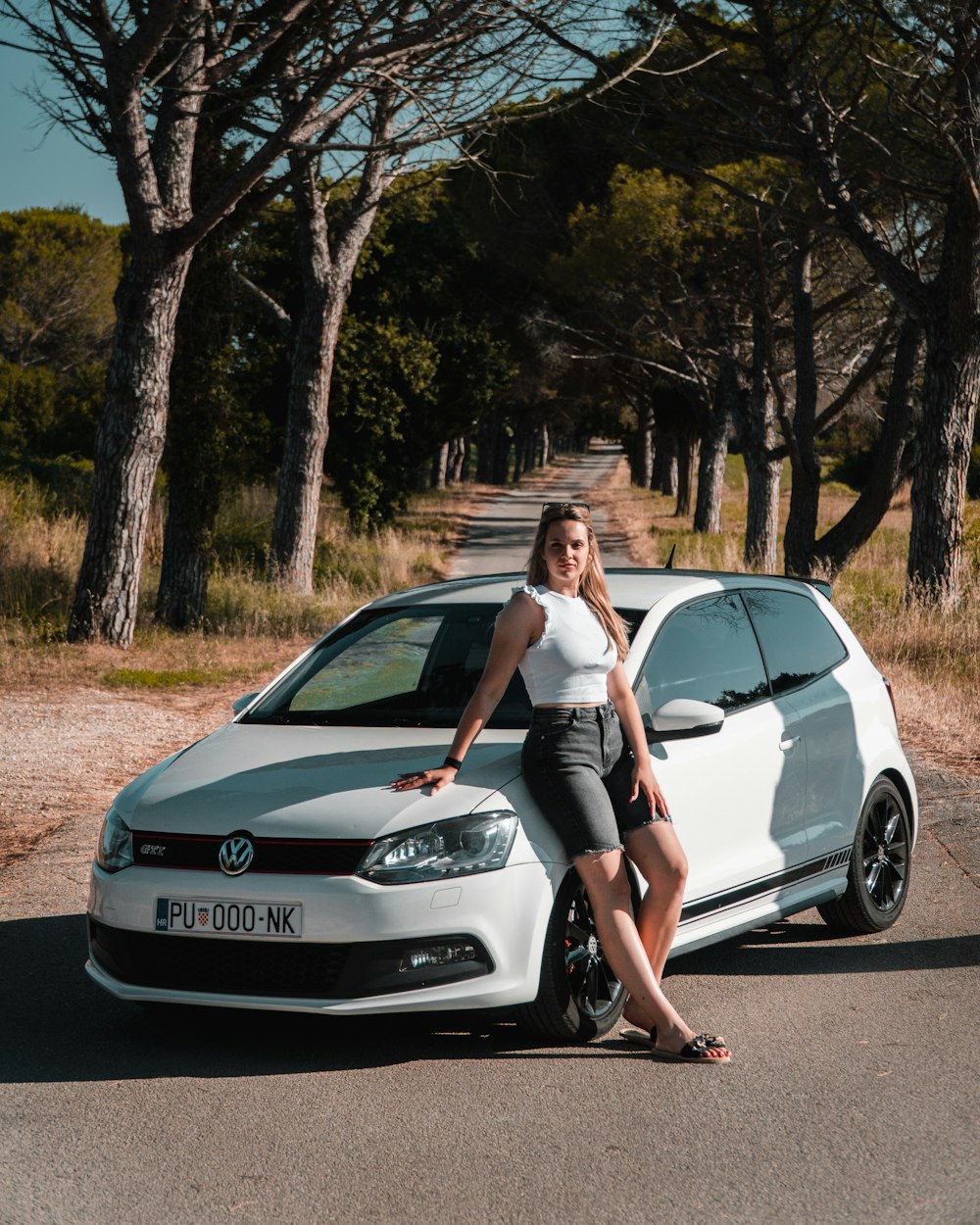 a woman sitting on the hood of a white car