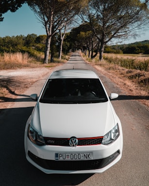 A pristine white Volkswagen Golf parked on a coastal road with ocean views.