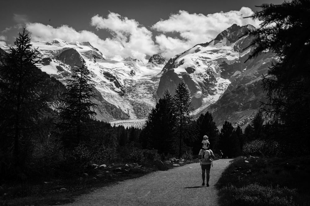 a black and white photo of a person walking down a road