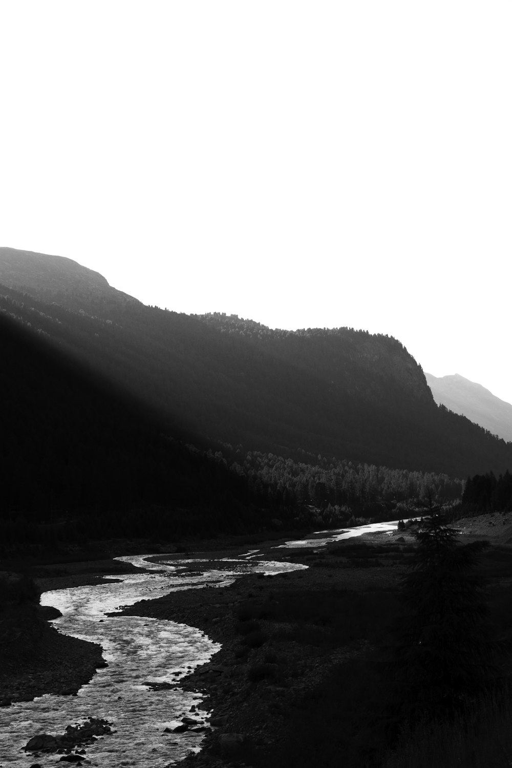 a black and white photo of a river in the mountains