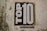A textured wall features a large poster with the words 'TOP 10' in bold black and white lettering. Below the main text, a smaller phrase reads 'solutions for the common good'.