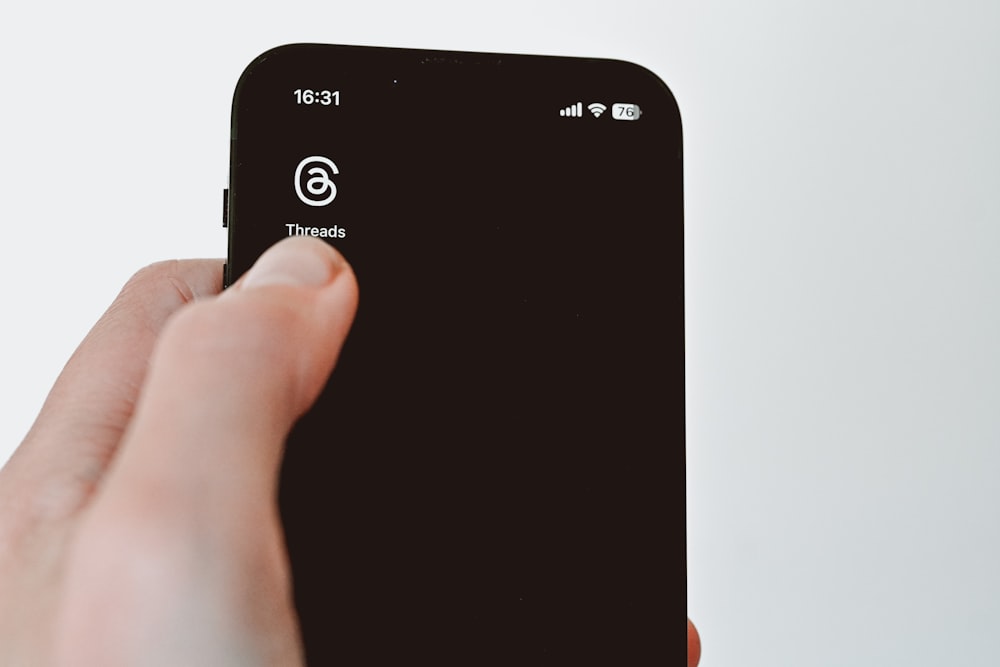 a hand holding a black cell phone with a white background