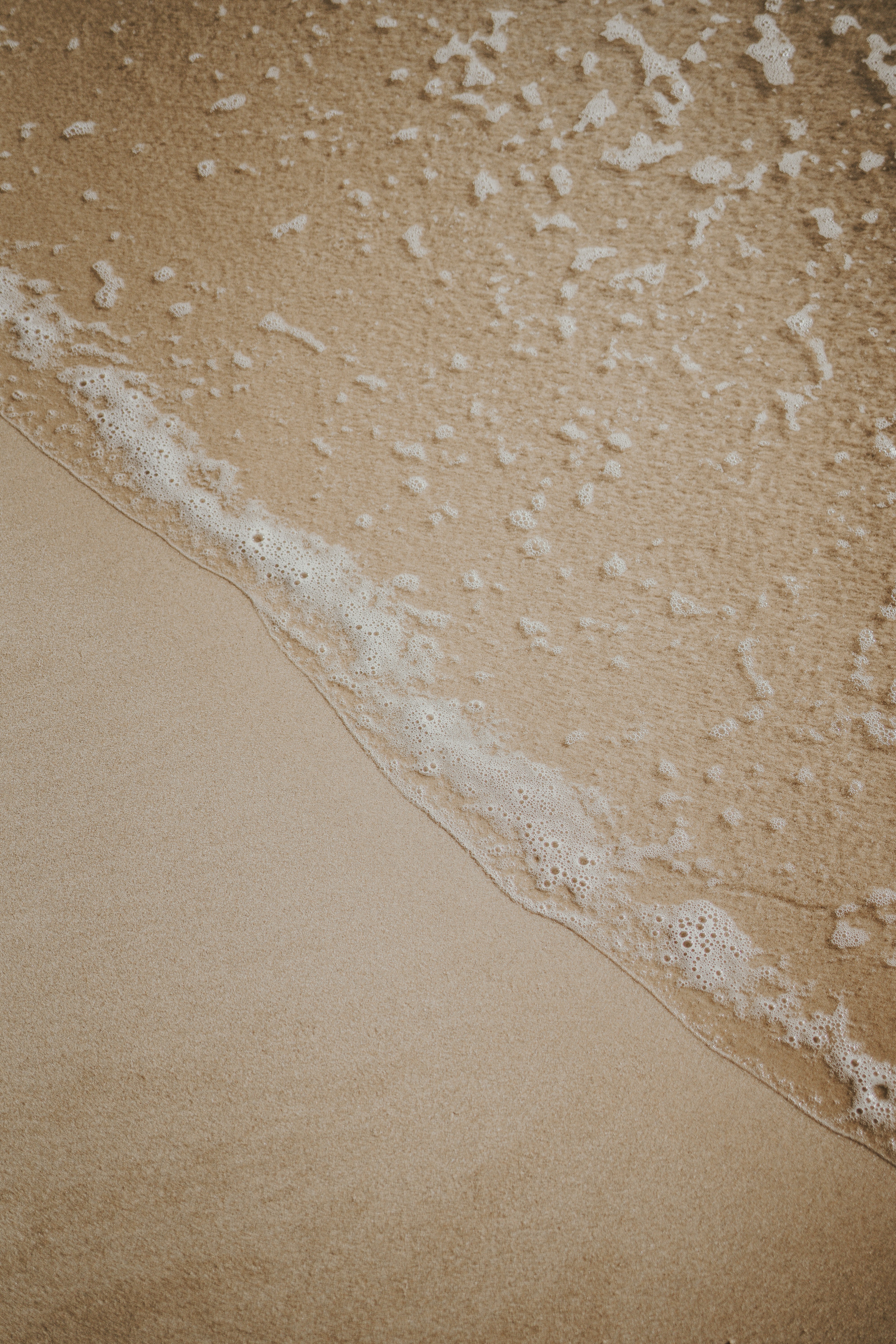 a sandy beach with a wave coming in to shore