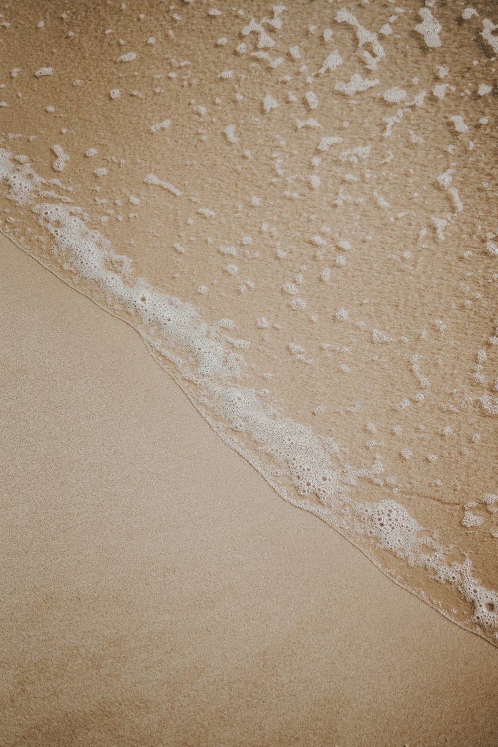 a sandy beach with a wave coming in to shore