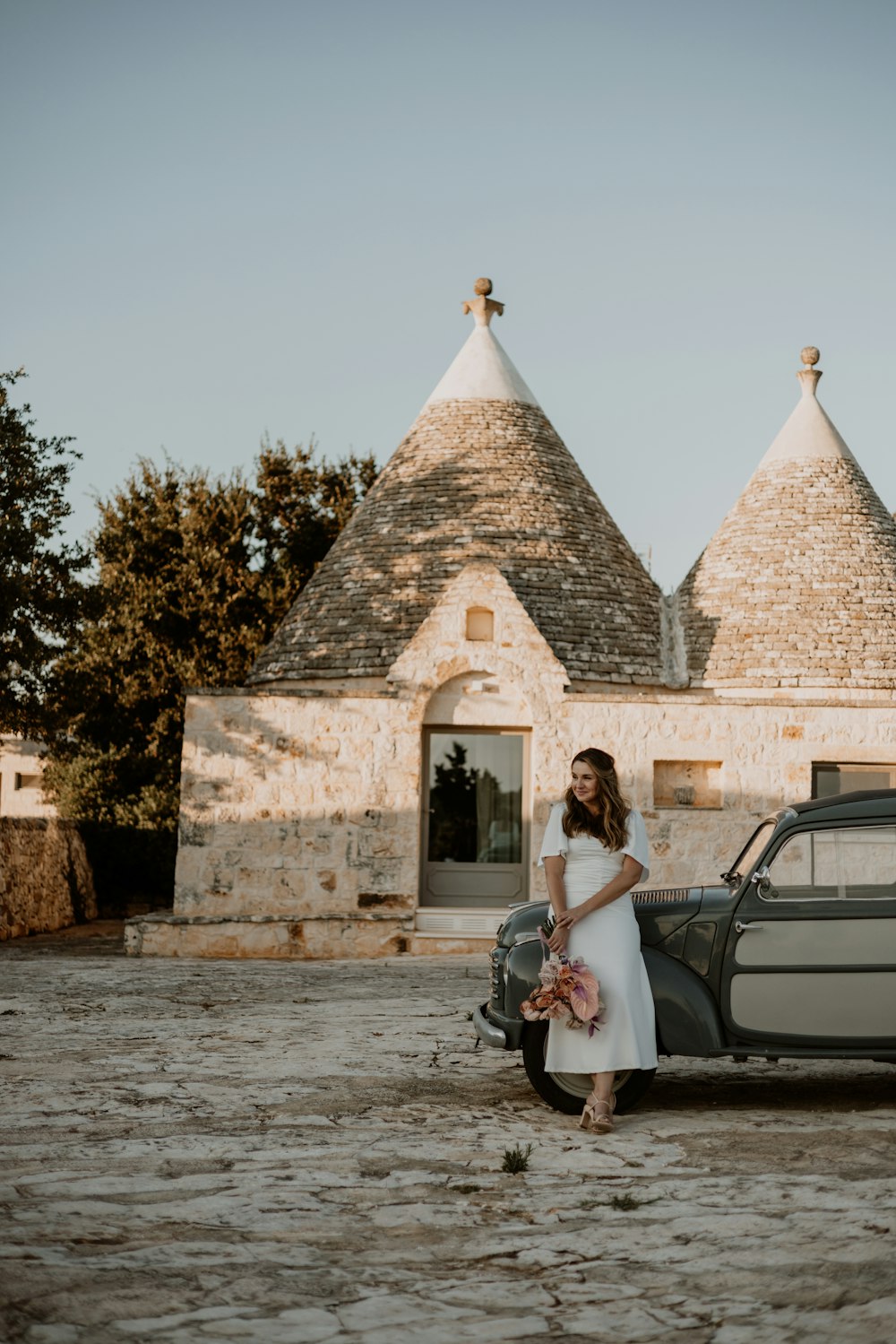 a woman in a white dress standing next to a car