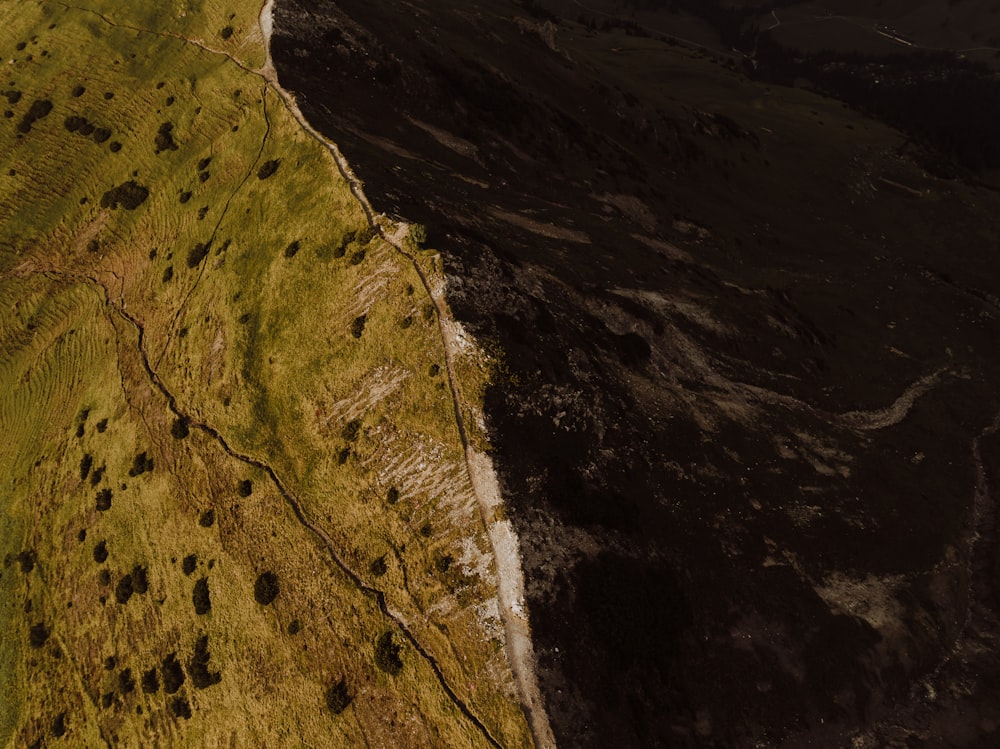 an aerial view of a grassy area with a hill in the background