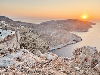 the sun is setting over the mountains and water