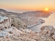 the sun is setting over the mountains and water