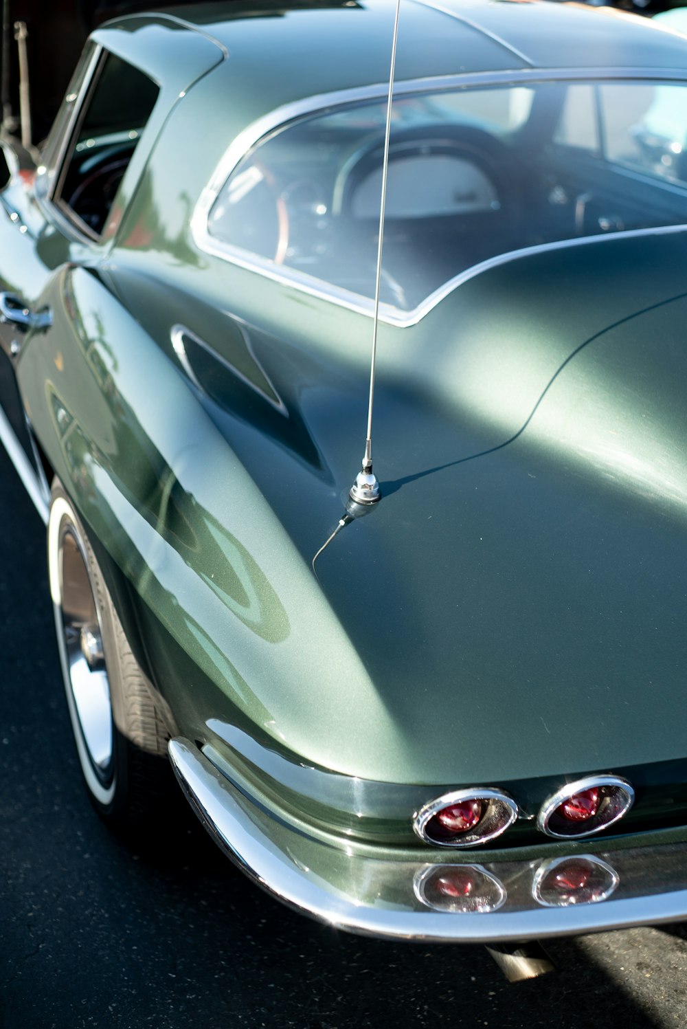 a green classic car parked in a parking lot