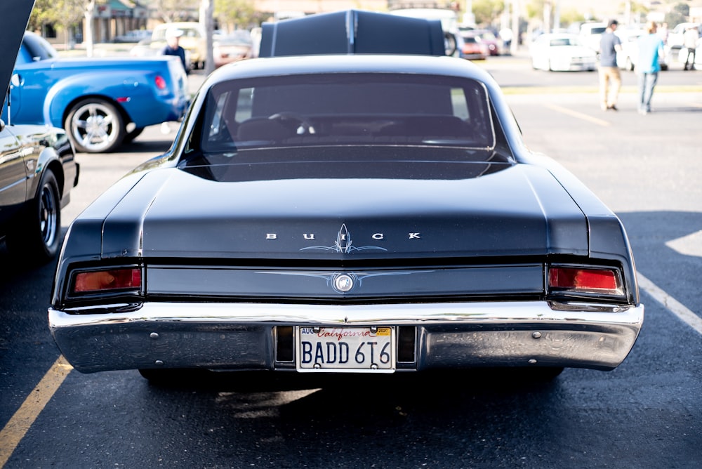 a black car parked in a parking lot next to other cars