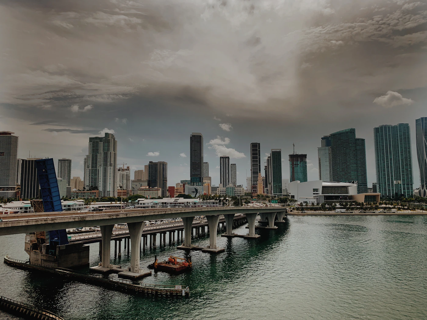 A bridge over the water toward the Miami skyline under a heavy sky. Causeways tie North Bay Village to both shores.