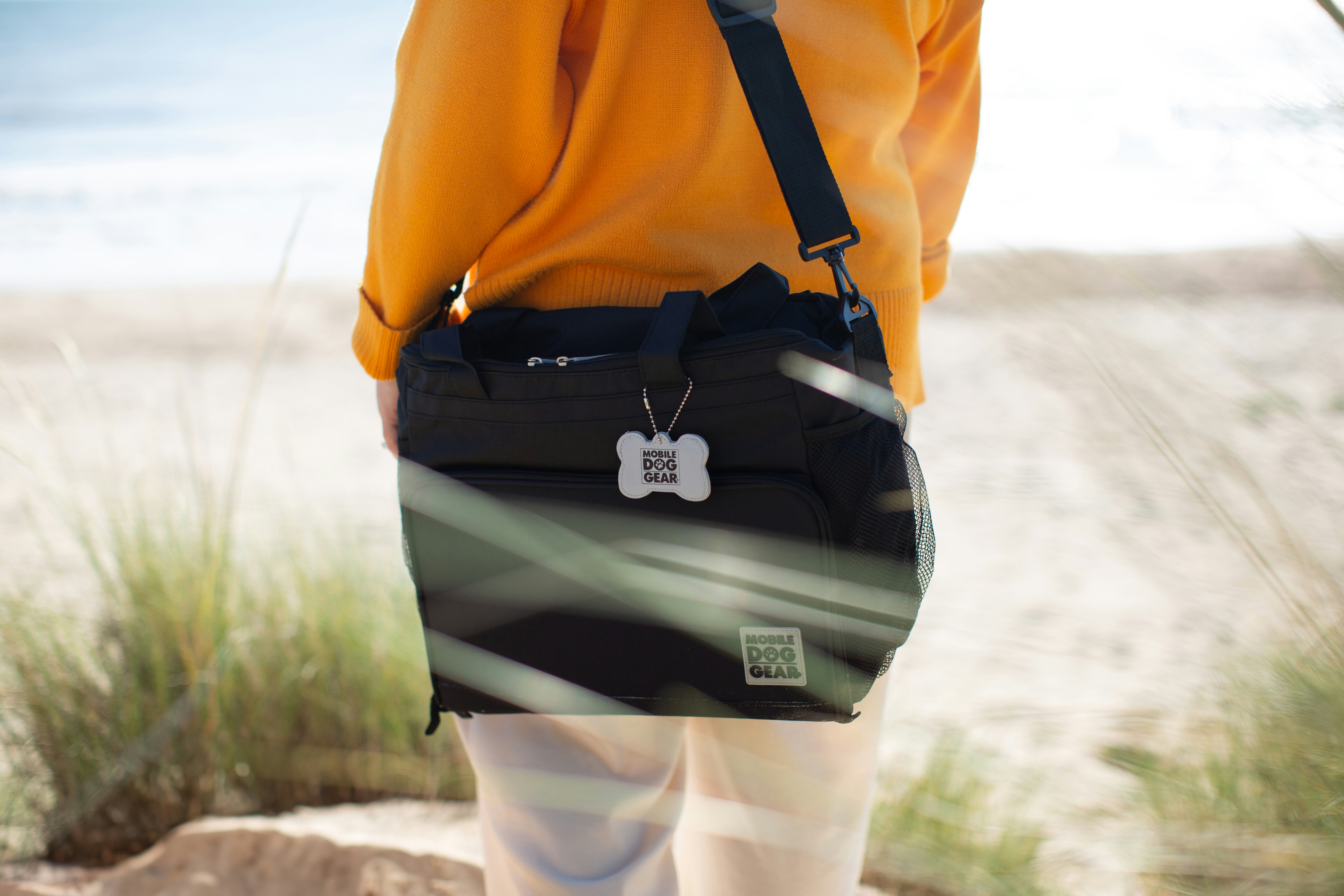une personne debout sur une plage tenant un sac noir