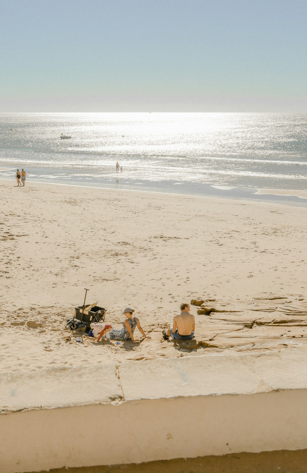a group of people sitting on top of a sandy beach
