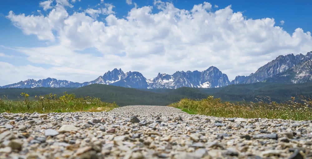 a gravel road with mountains in the background