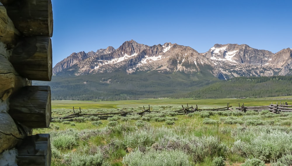 a field with a fence and mountains in the background