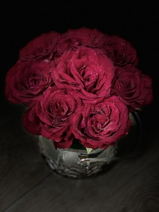 Elegant bouquet of deep red roses in a crystal vase on a marble table.