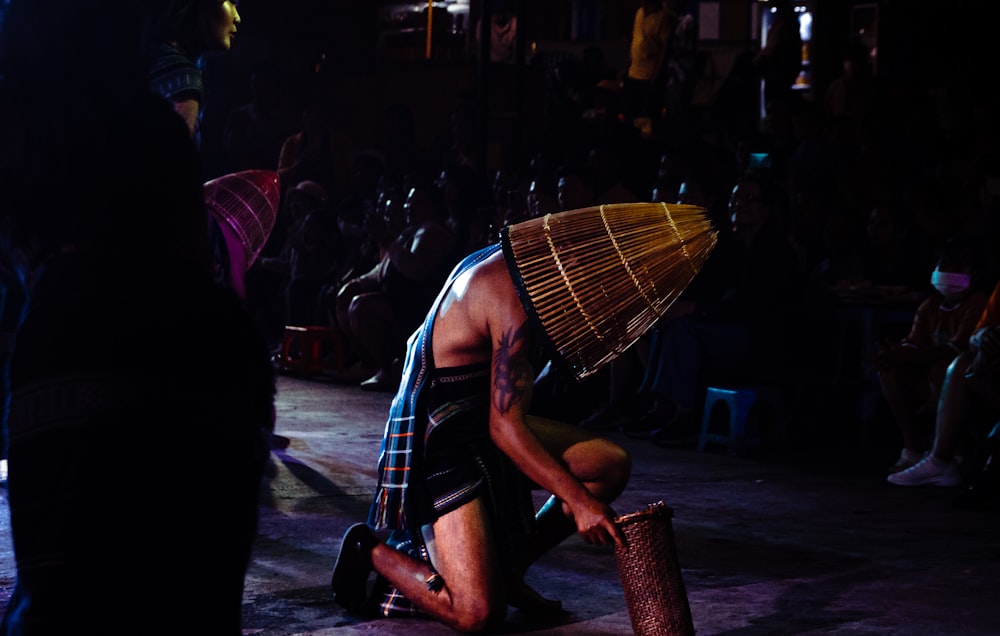 a man kneeling down with a bamboo umbrella on his head