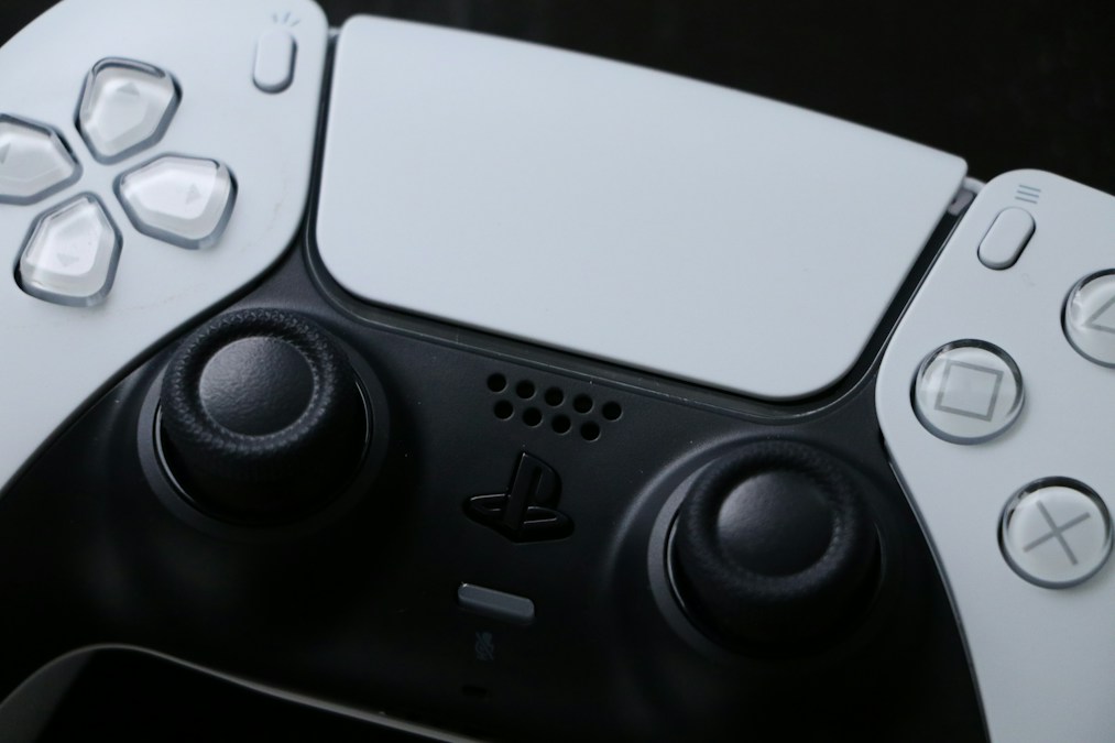 Gros plan sur une manette de console blanche et noire, ses deux joysticks et son pavé tactile, en illustration